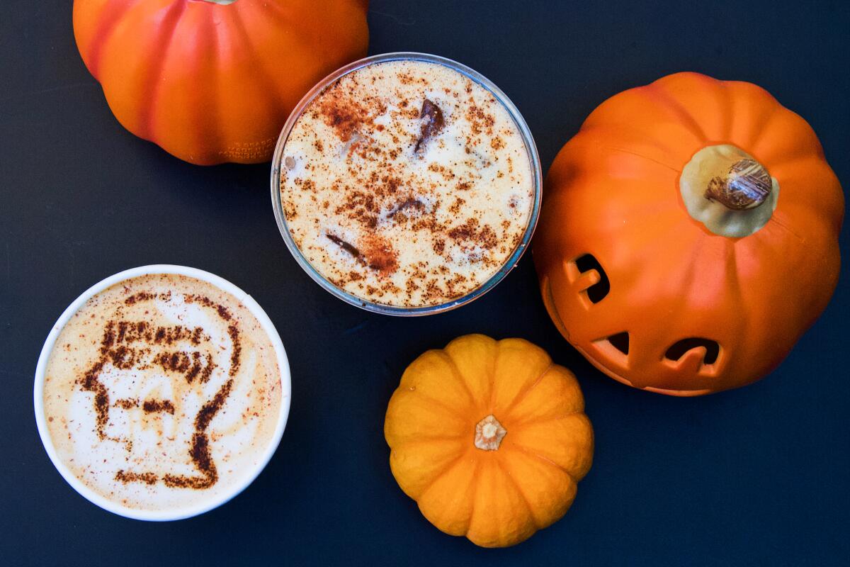 Two cups with foamy drinks, seen from overhead, with small pumpkin and Jack-o'-lantern.