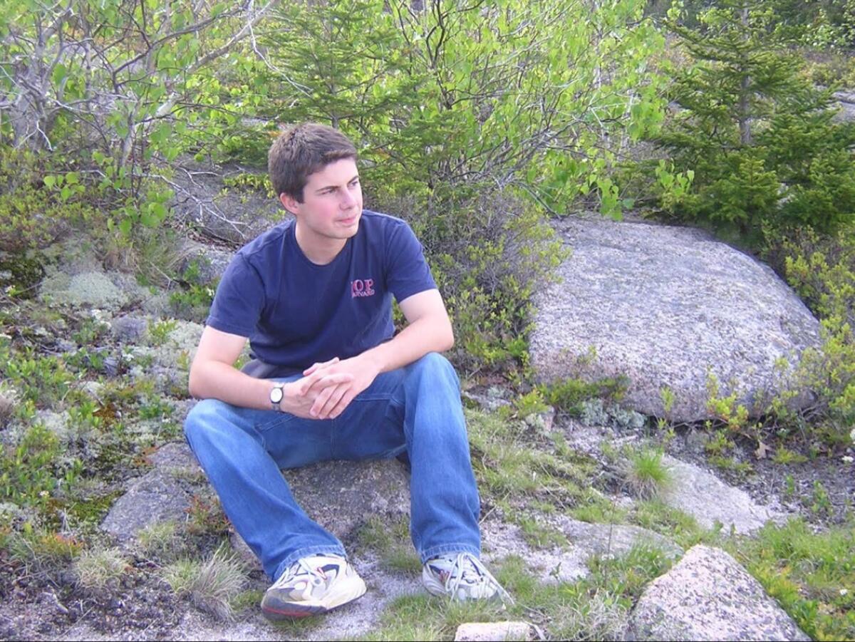 A young person sits on a rock.