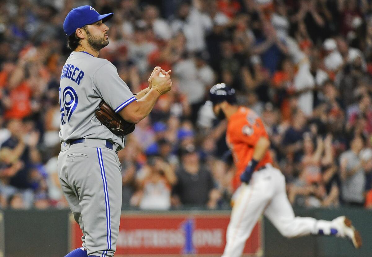 Toronto Blue Jays relief pitcher Mike Bolsinger, left, walks off the mound as Houston Astros' Marwin Gonzalez rounds the bases after hitting a three-run home run on Aug. 4, 2017.