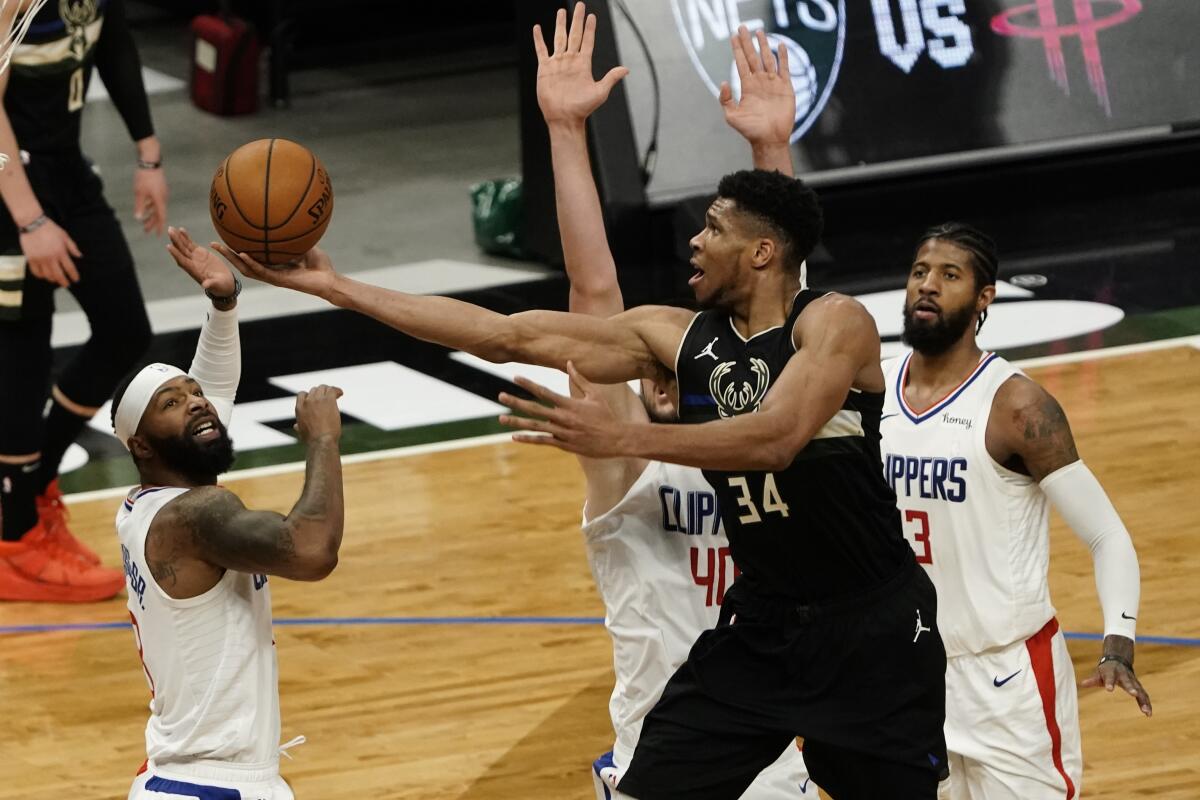 Milwaukee's Giannis Antetokounmpo drives for a layup in front of the Clippers' Marcus Morris, Ivica Zubac and Paul George.