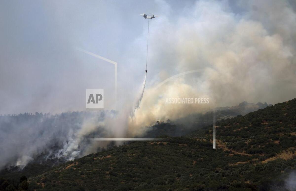 A helicopter drops water to extinguish a fire raging across a forested area in Odemis, near ?zmir, Turkey, on Friday.