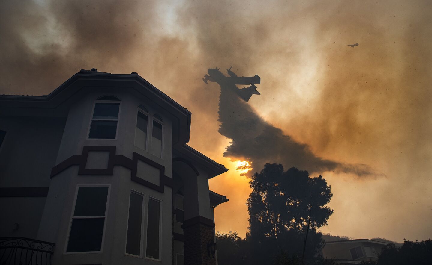 An air tanker drops a load of water to save a home in Lake Elsinore, Calif.