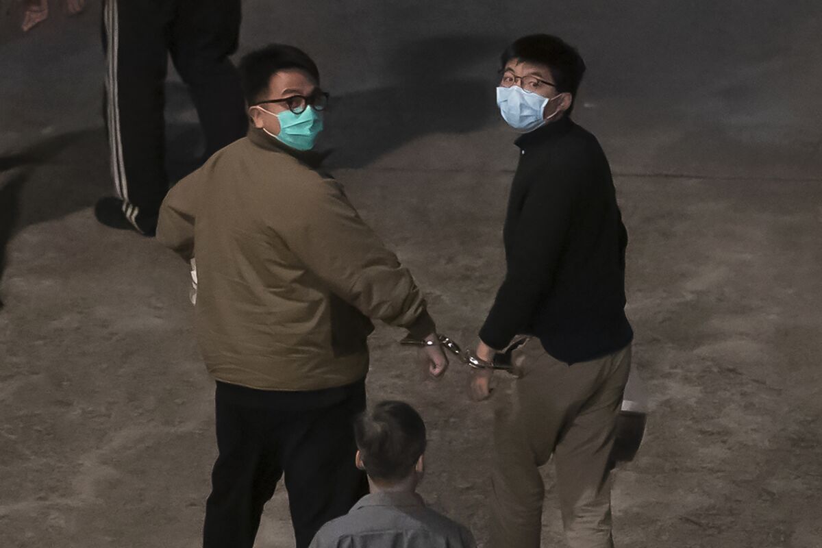 Hong Kong activists Joshua Wong, right, and Ivan Lam, left, are escorted by Correctional Services officers to prison, in Hong Kong, Wednesday, Dec. 2, 2020. Three prominent Hong Kong pro-democracy activists, Wong, Lam, and Agnes Chow were sentenced to jail Wednesday for a protest outside police headquarters as authorities step up a crackdown on opposition to tighter Chinese control of the territory. (AP Photo/Kin Cheung)