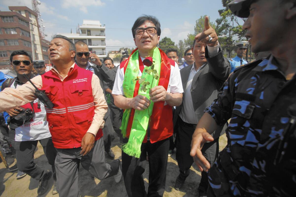 Chinese actor Jackie Chan, center, walks with officials in Katmandu, Nepal, last month during a relief program with the Chinese Red Cross. Chinese nonprofits are expanding their reach just as the government is considering a law to restrict foreign nonprofits working in China.
