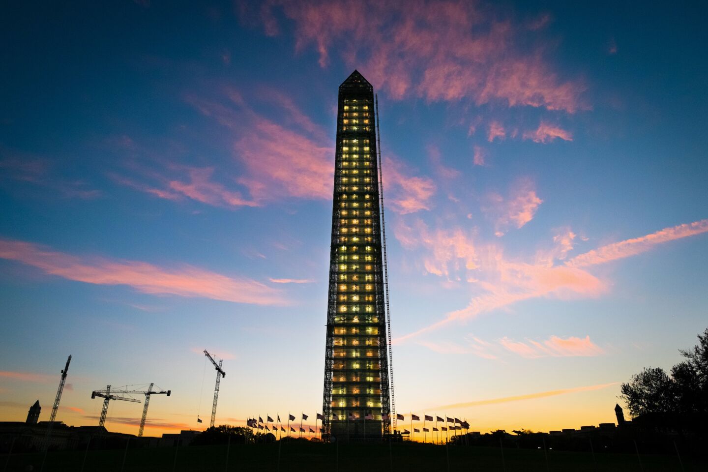 The sun rises behind the scaffolding-clad Washington Monument in Washington.