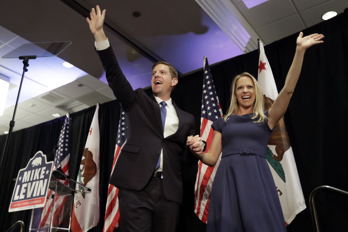 Democratic congressional candidate Mike Levin and and his wife Chrissy wave to supporters in Del Mar early Nov. 7 .