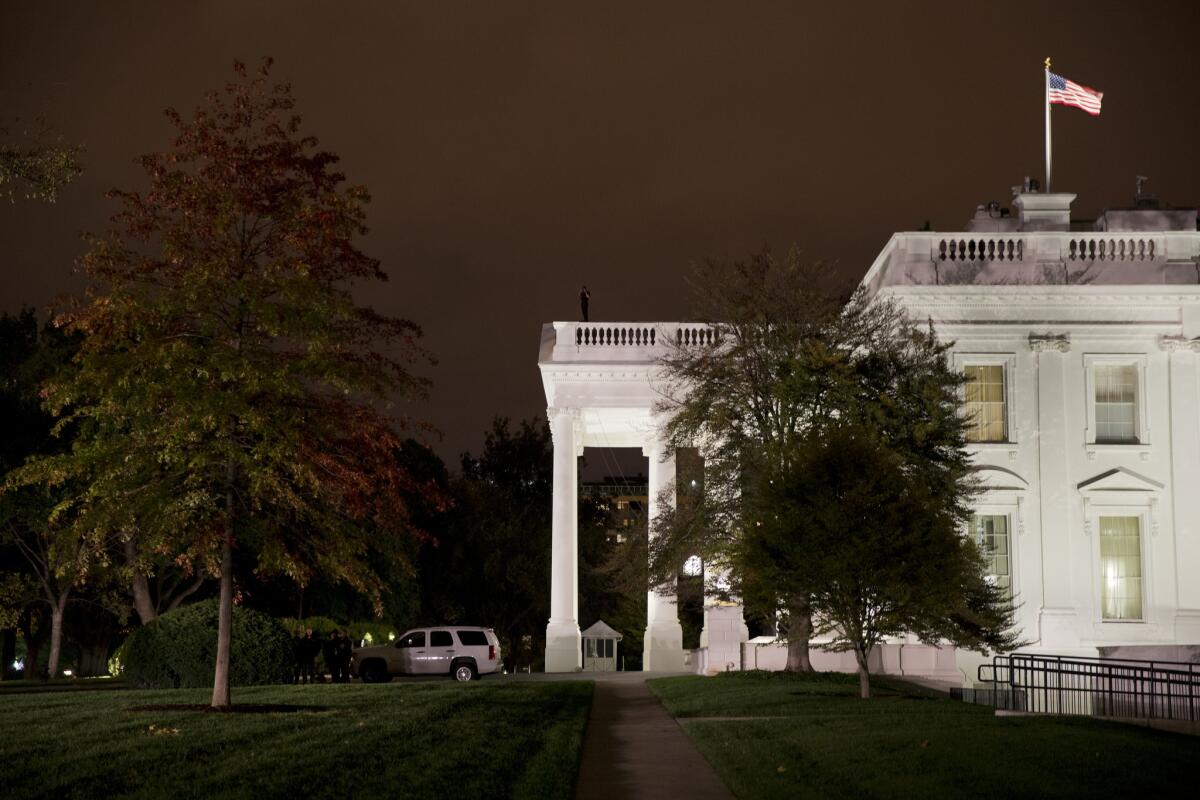 Secret Service agents gather on the White House's North Lawn and another agent surveys from the rooftop Oct. 22 after a man who jumped the fence was arrested.