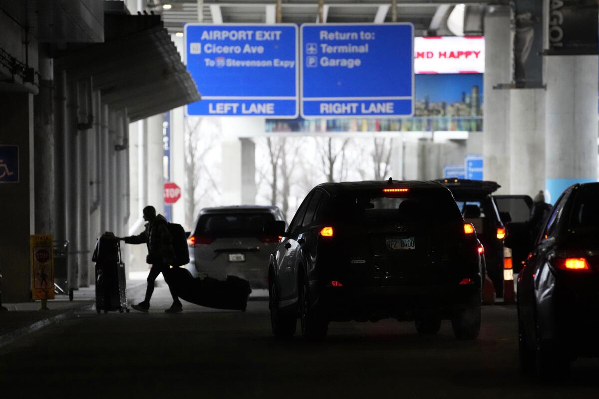 An airline passenger walks between ride-hailing share vehicles after arriving at Chicago's Midway airport on Tuesday.