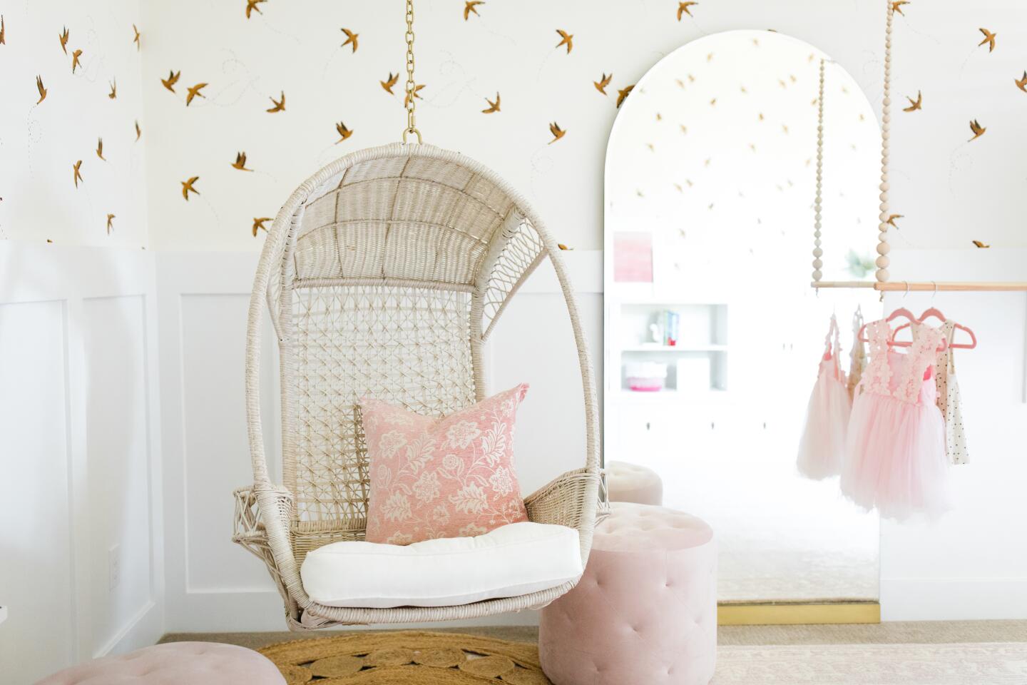 The playroom has pale pink accents, along with timeless wainscoting and wallpaper in a flying-sparrow pattern.