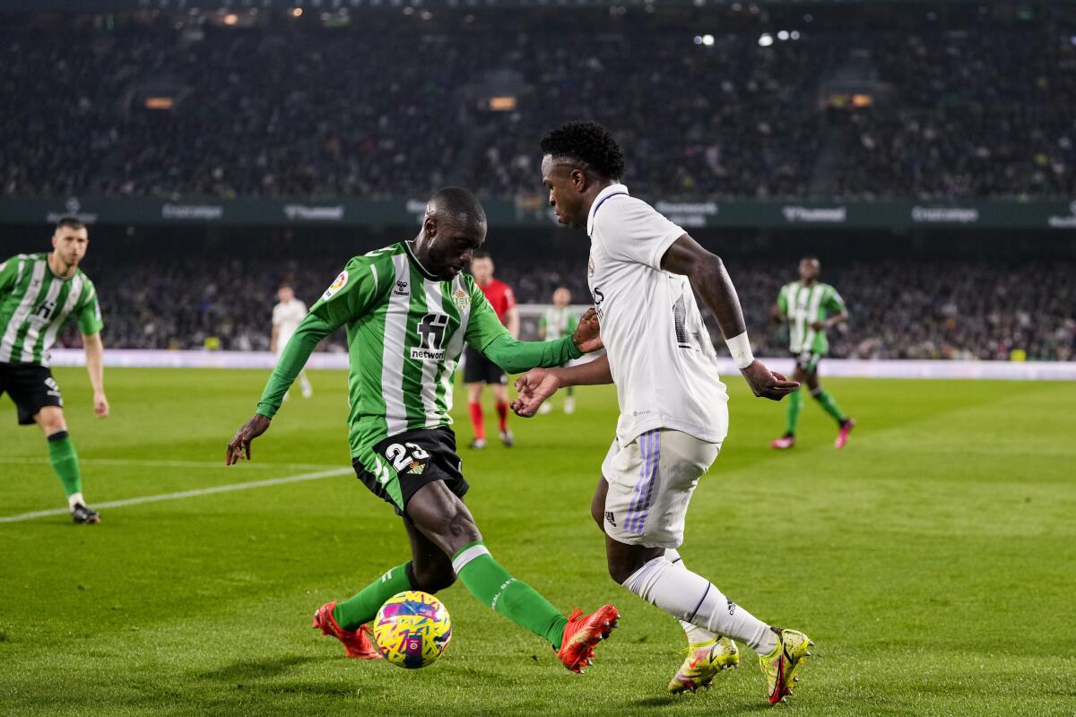 Vinicius Junior (derecha) del Real Madrid y Youssouf Sabaly del Betis pugna por el balón 