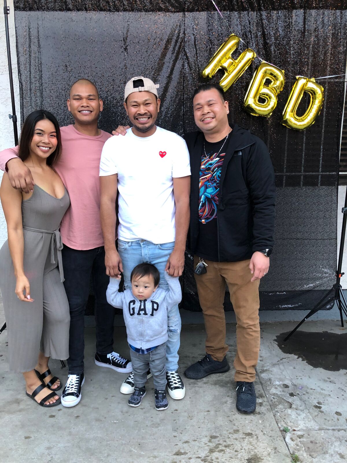 Rickie Chhoeun, in white T-shirt, poses at a birthday party with two brothers and his sister at her Long Beach home in June 2019.