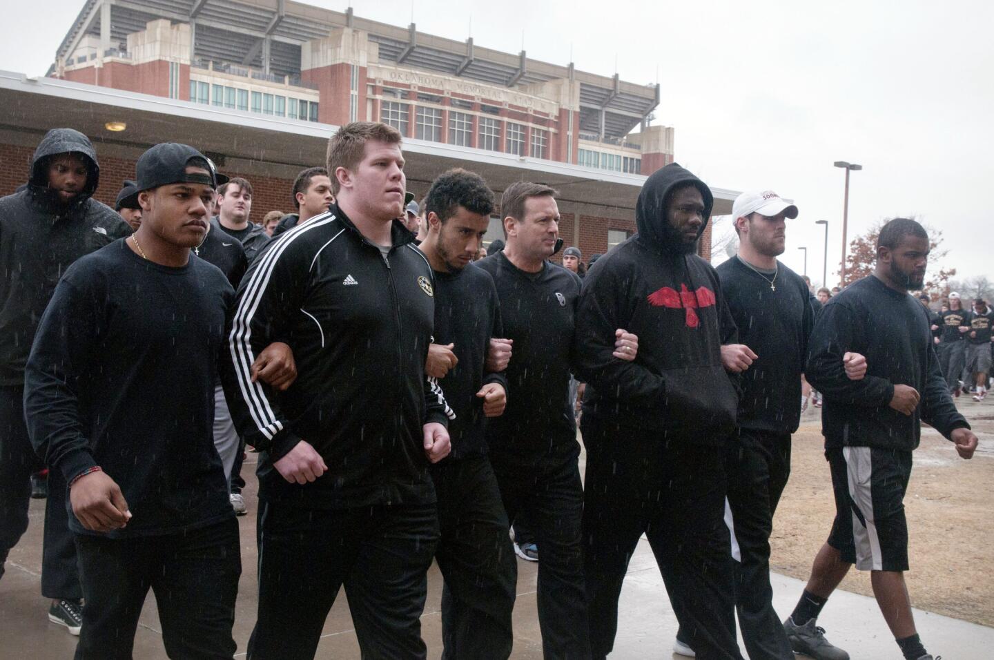 The University of Oklahoma football team and coaches walk to practice wearing all black in protest of the Sigma Alpha Epsilon fraternity's racist chant.