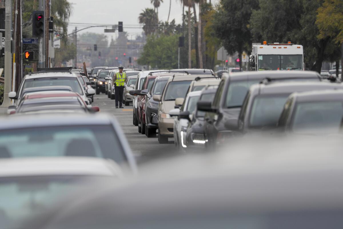 Cars line up on Sepulveda Boulevard to get meal packages provided by LAUSD at a grab-and-go food center at Francisco Sepulveda Middle School in North Hills. 