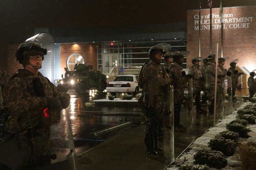 Missouri National Guard troops stand in the rain outside the Ferguson Police Station on Nov. 26.