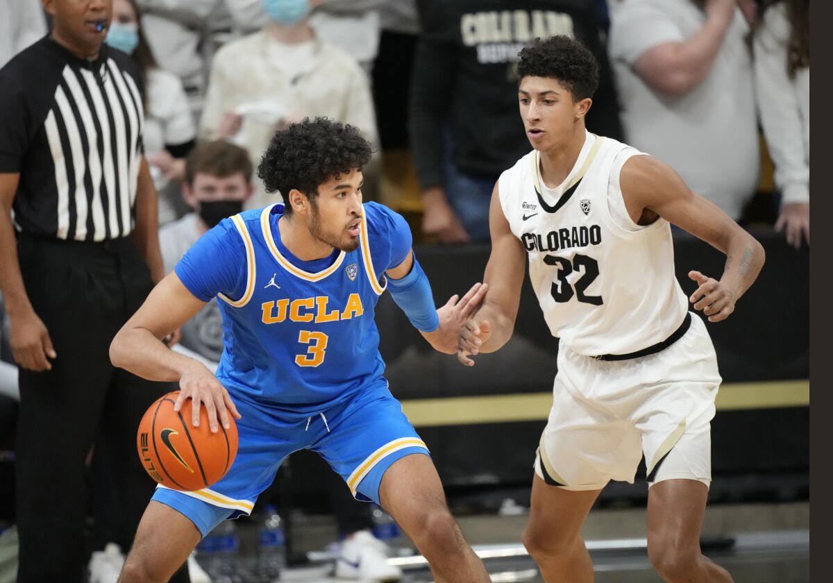 UCLA guard Johnny Juzang, left, looks to pass the ball as Colorado guard Nique Clifford defends in the second half.