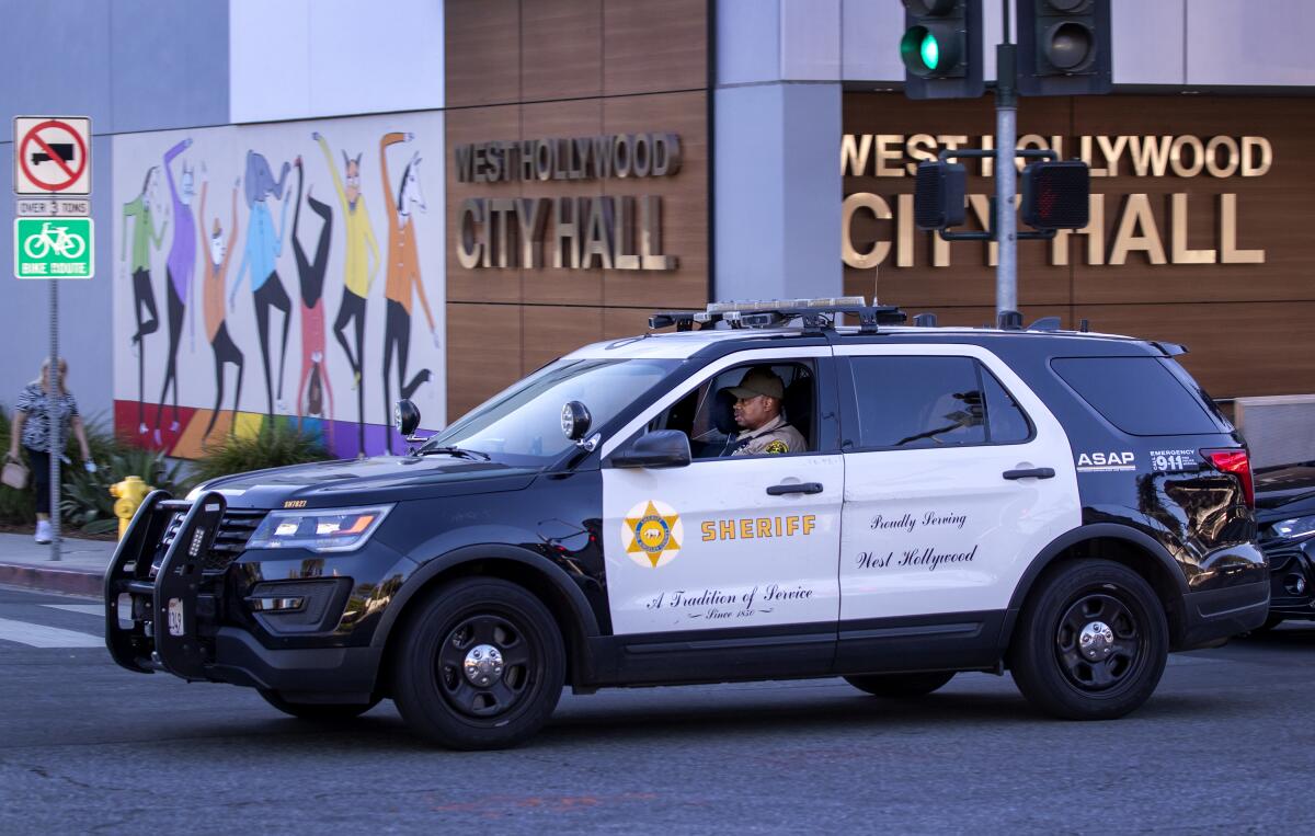 A deputy drives past West Hollywood City Hall in a Sheriff's Department SUV on Oct. 28, 2021.