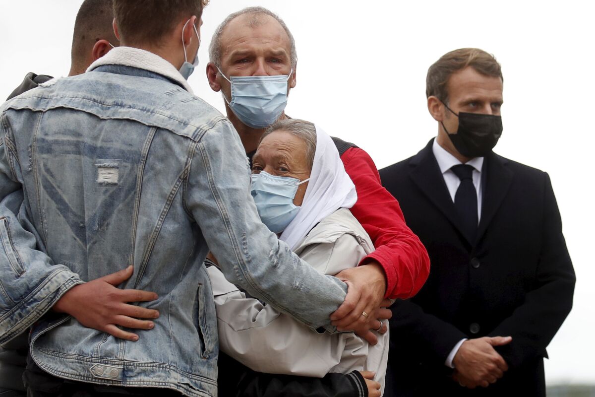 FILE - France President Emmanuel Macron, right, stands as Sophie Petronin, center, a French aid worker held hostages for four years by Islamic extremists in Mali, is greeted by relatives upon her arrival at the Villacoublay military airport near Paris, Friday Oct. 9, 2020. Malian authorities say they are actively searching for Sophie Petronin, a French-Swiss woman who spent four years as an al-Qaida hostage and who now has returned illegally to the West African country. Sophie Petronin spent years working in Mali before her abduction and is believed to have returned quietly earlier this year. (Gonzalo Fuentes, Pool Photo via AP, File)