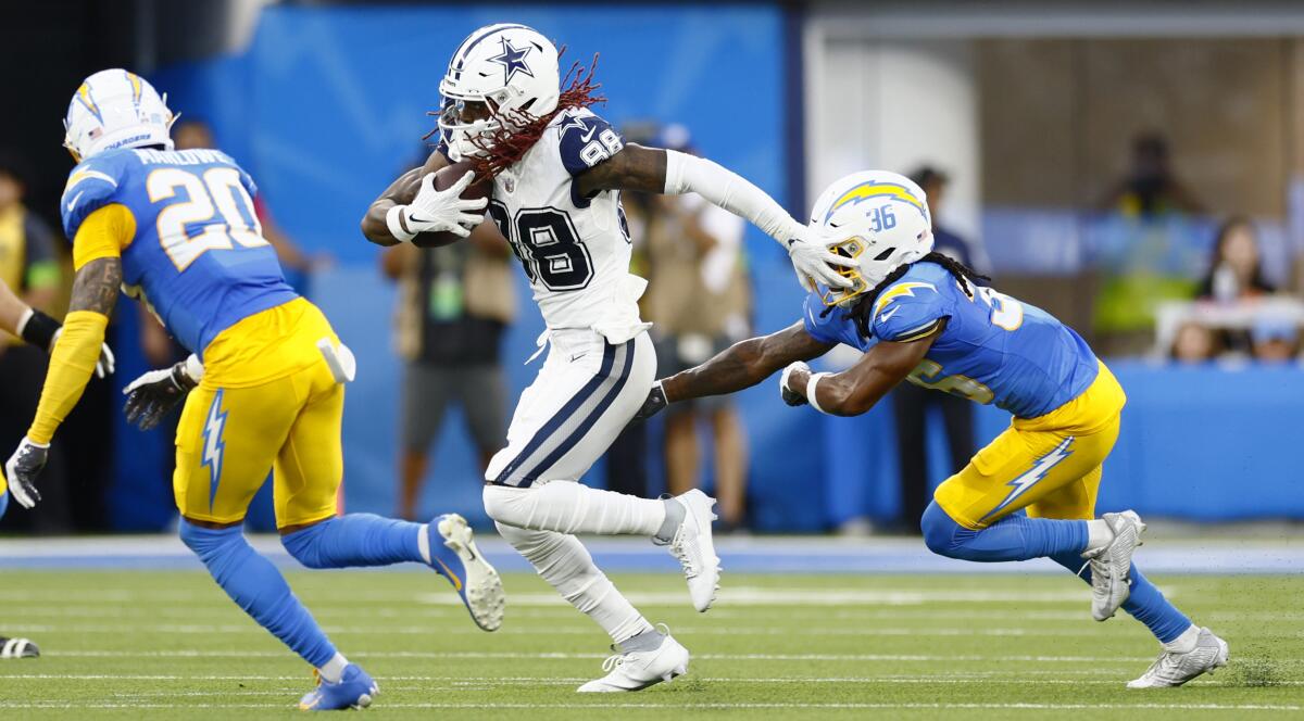 Dallas Cowboys wide receiver CeeDee Lamb runs between the Chargers' Dean Marlowe and Ja'Sir Taylor during the first half.