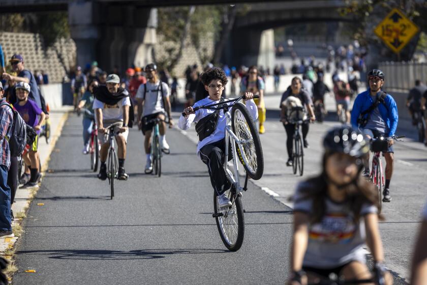 Los Angeles, CA - October 29: A bicyclist does a wheelie as he joins thousands of bicyclists, rollerbladers, skateboarders, walkers and runners enjoy the Arroyo Seco Parkway (110 Freeway) during ArroyoFest, which is closed in the morning hours to vehicle traffic and open to bikes and pedestrians on the freeway between Northeast Los Angeles and South Pasadena Sunday, Oct. 29, 2023. The celebration known as 626 Golden Streets ArroyoFest is a sequel to the first ArroyoFest, held 20 years ago. (Allen J. Schaben / Los Angeles Times)