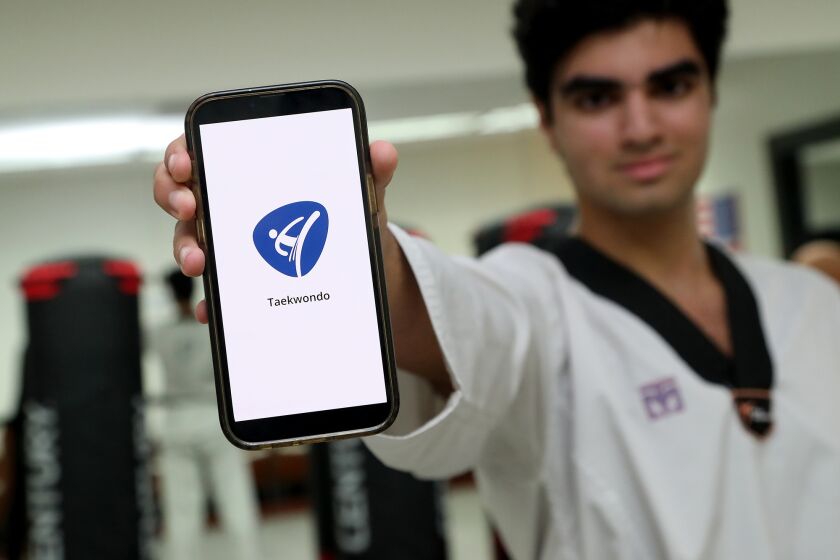 Sage Hill School senior Aiden Kiani, 17, recently launched a free Taekwondo app to help his master, John Seock, at Sunrise Martial Arts in Newport Beach. (Kevin Chang / Daily Pilot)