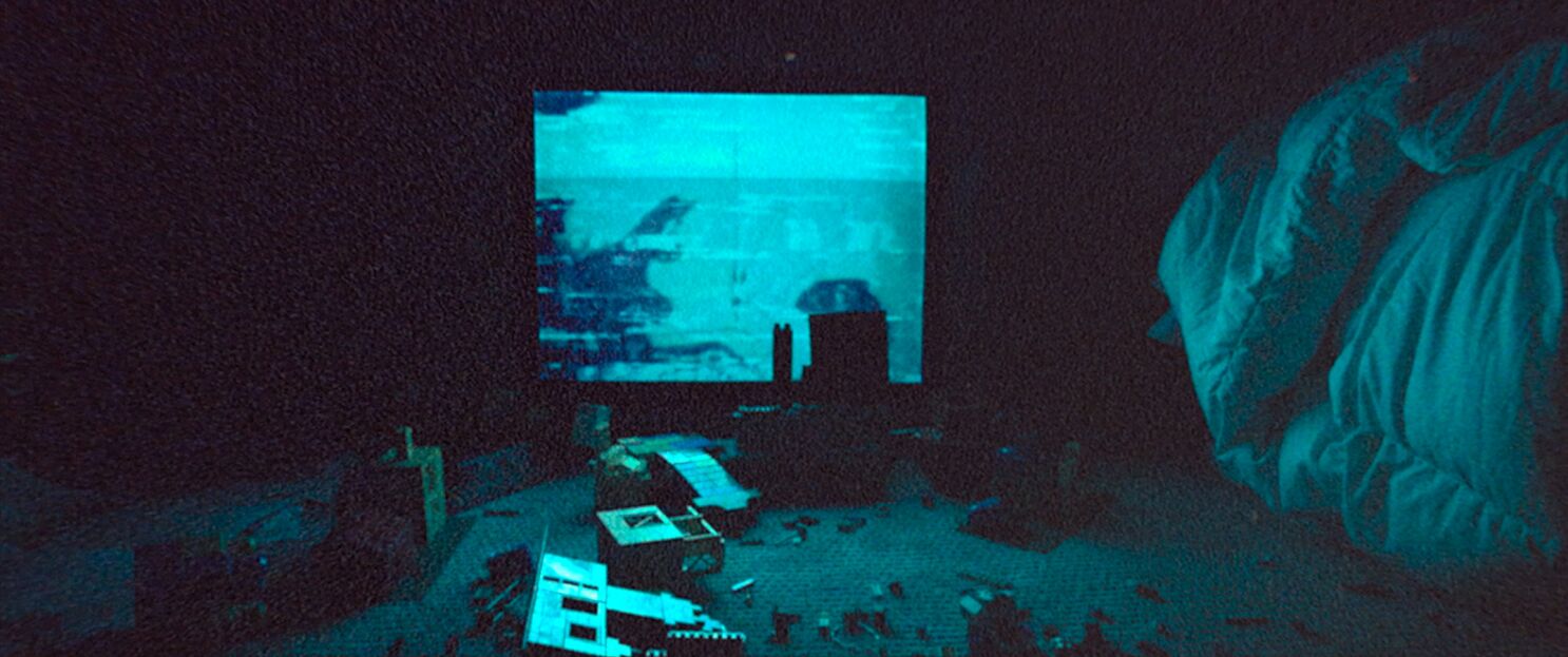 Lego blocks scattered across the floor in front of an old TV in the darkness