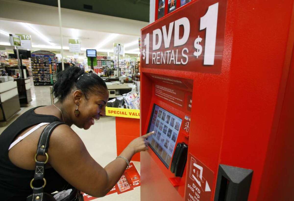 A woman selects a DVD at a Redbox kiosk in 2009. Disney wants the company to stop selling codes for digital versions of its movies.