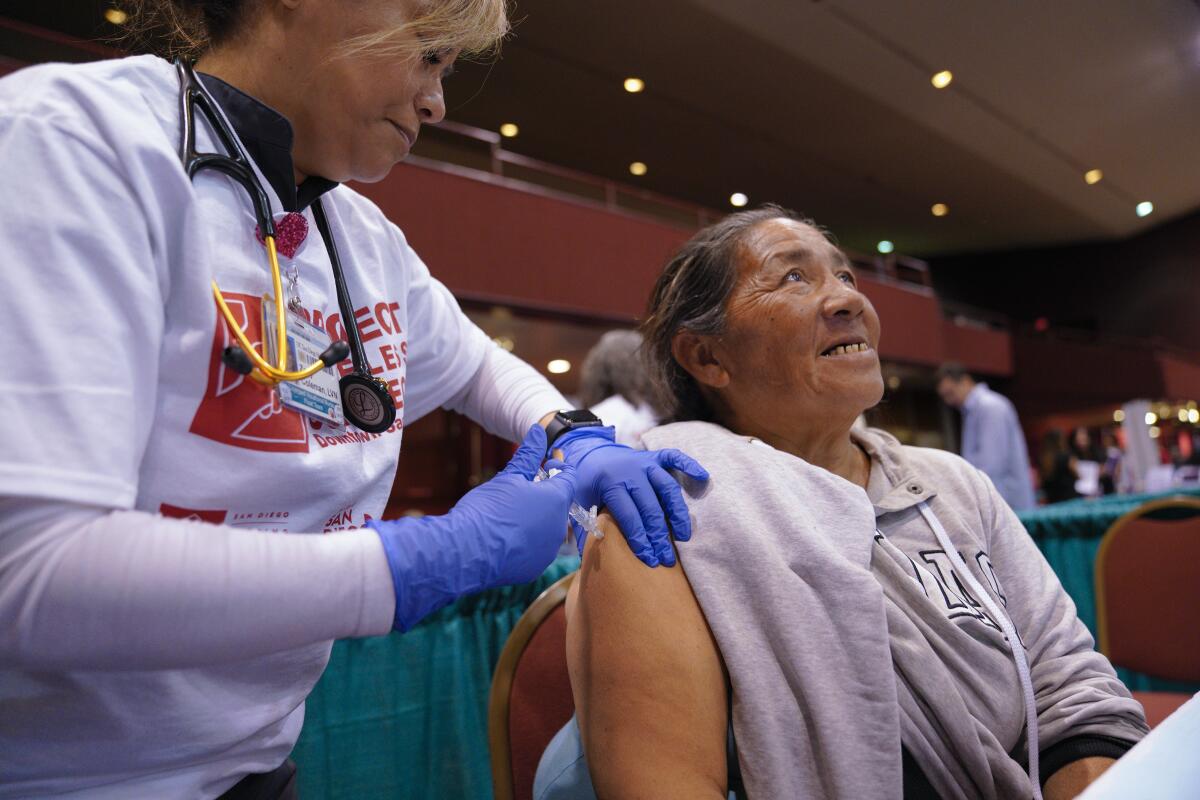 Azucena Coleman RN gives Helen Christy two separate flu injections.