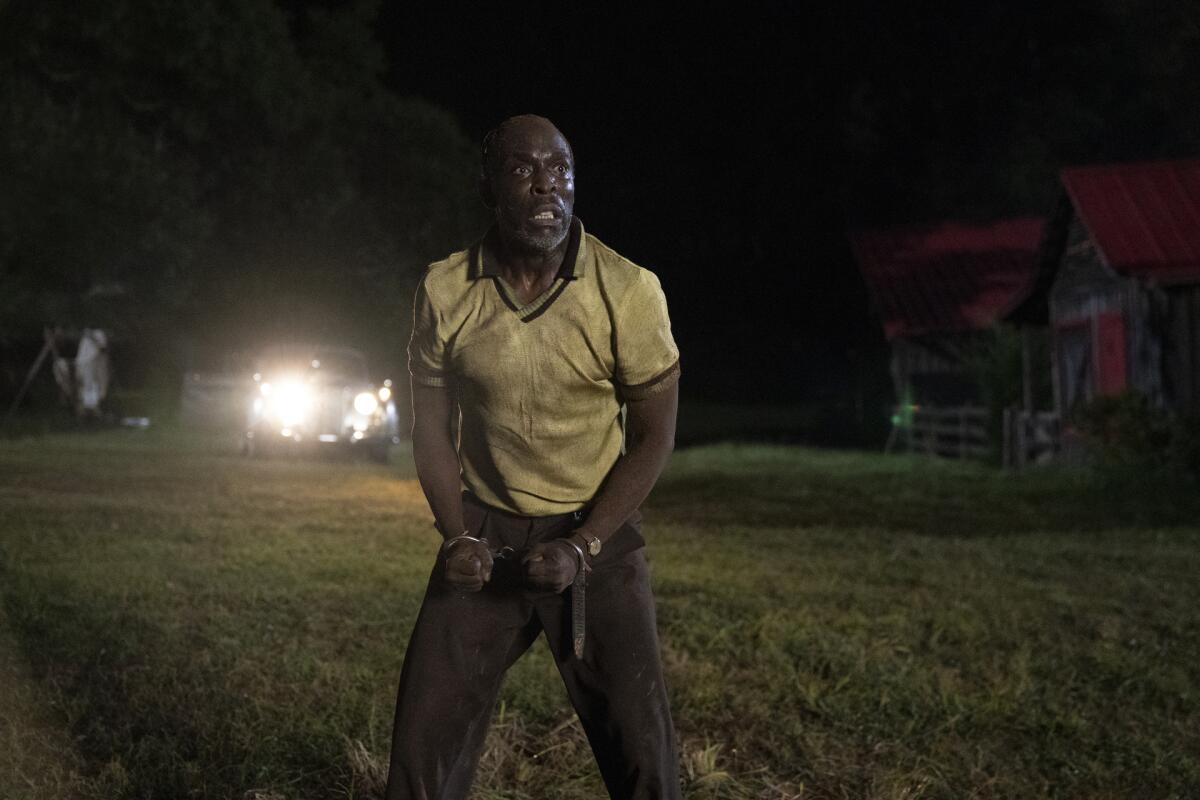 A man in handcuffs stands in the dark