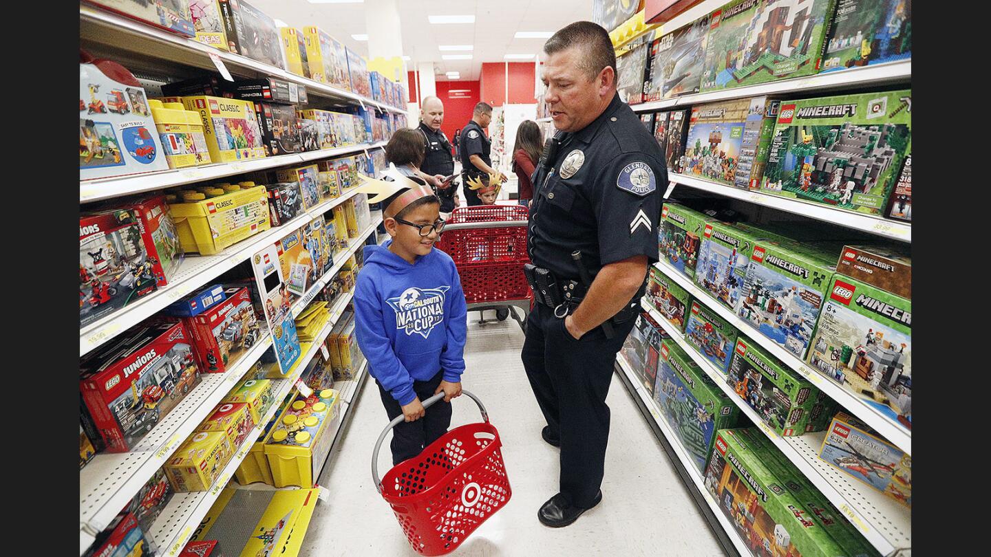 Glendale police officer Nick Orloff gives Lego ideas to Nathaniel Aviles, 9, who is scanning everything to make a decision while they both shop as part of the Glendale Police's Cops for Kids program at Target at the Glendale Galleria on Friday, December 1, 2017. This year, the program helped 40 children each receiving $150 to spend on gifts.