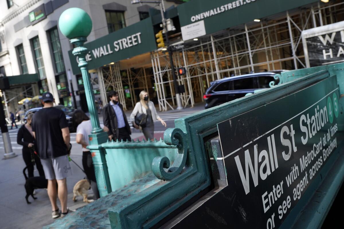 People walk in New York past signs that say Wall Street