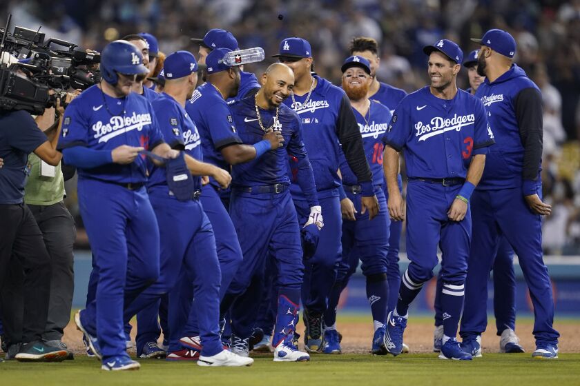 Mookie Betts (centro), de los Dodgers de Los Ángeles, recibe la felicitación de sus compañeros tras sacudir un sencillo que dio la victoria a su equipo en el último inning del juego de la MLB contra los Diamondbacks de Arizona, en Los Ángeles, el 22 de septiembre de 2022. (AP Foto/Ashley Landis)