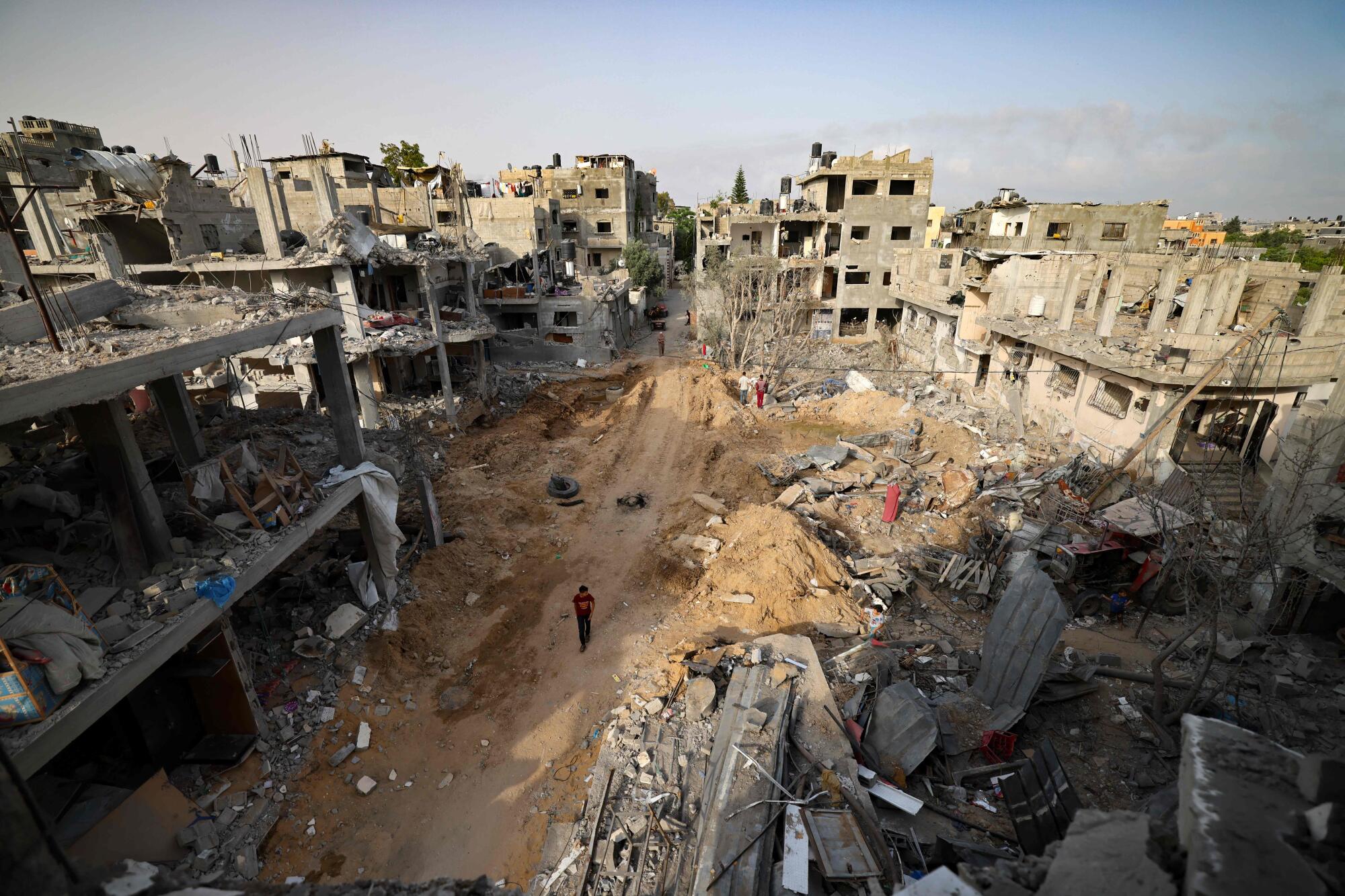 A man walks between ruined buildings