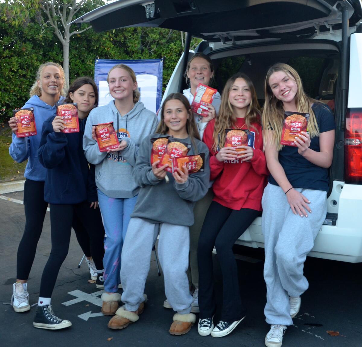 The Newport Beach Girl's Water Polo Club hands out Rice-A-Roni during the Trunk & Pack food drive.