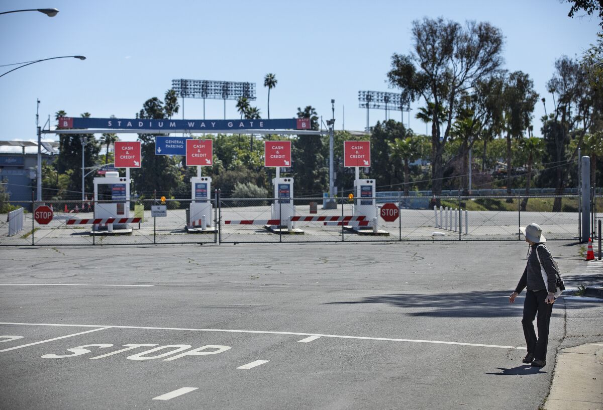 A pedestrian looks at an entrance to Dodger Stadium that is closed on what would have been opening day if not for the coronavirus outbreak.