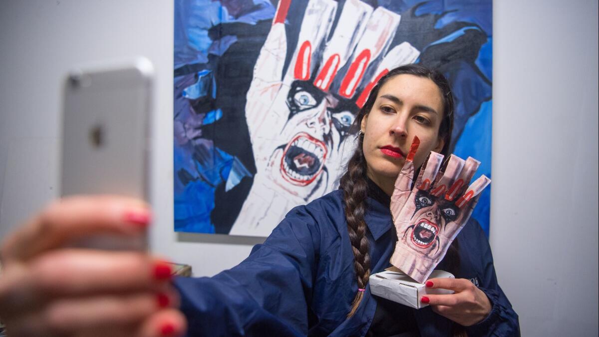 Bay Area artist Laura Rokas snaps an Instagram selfie in front of her artwork at her studio in San Francisco.