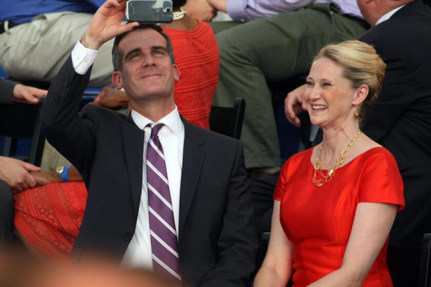Eric Garcetti, seated next to his wife, Amy Wakeland, shoots video of the proceedings after being sworn in as mayor of Los Angeles.