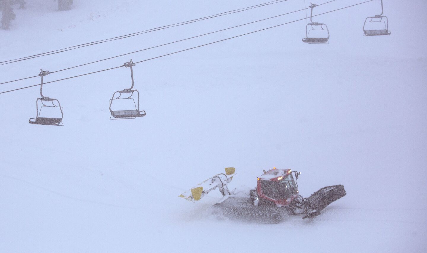 A snowcat moves snow in near whiteout conditions on the slopes at Mammoth Mountain.