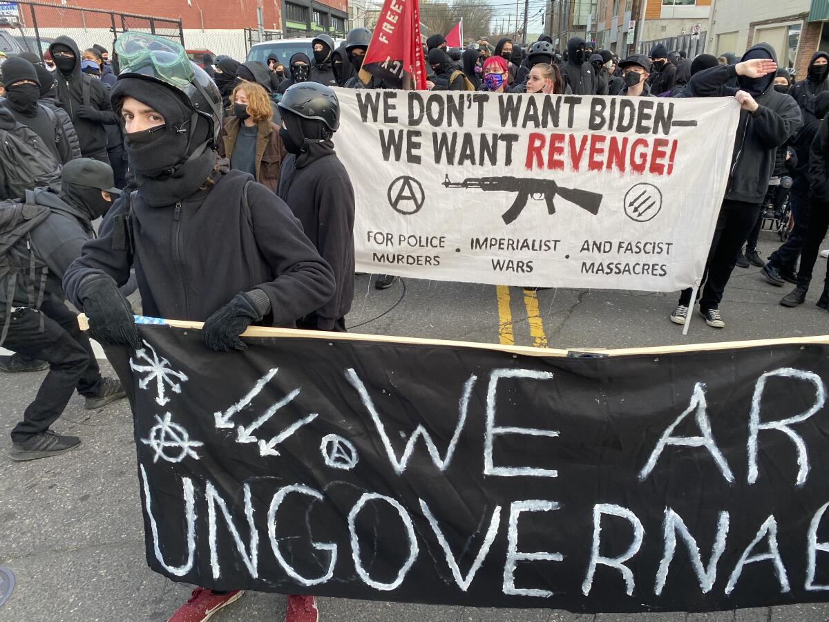 Anarchists march in Portland on Wednesday, carrying a banner opposing President Joe Biden.