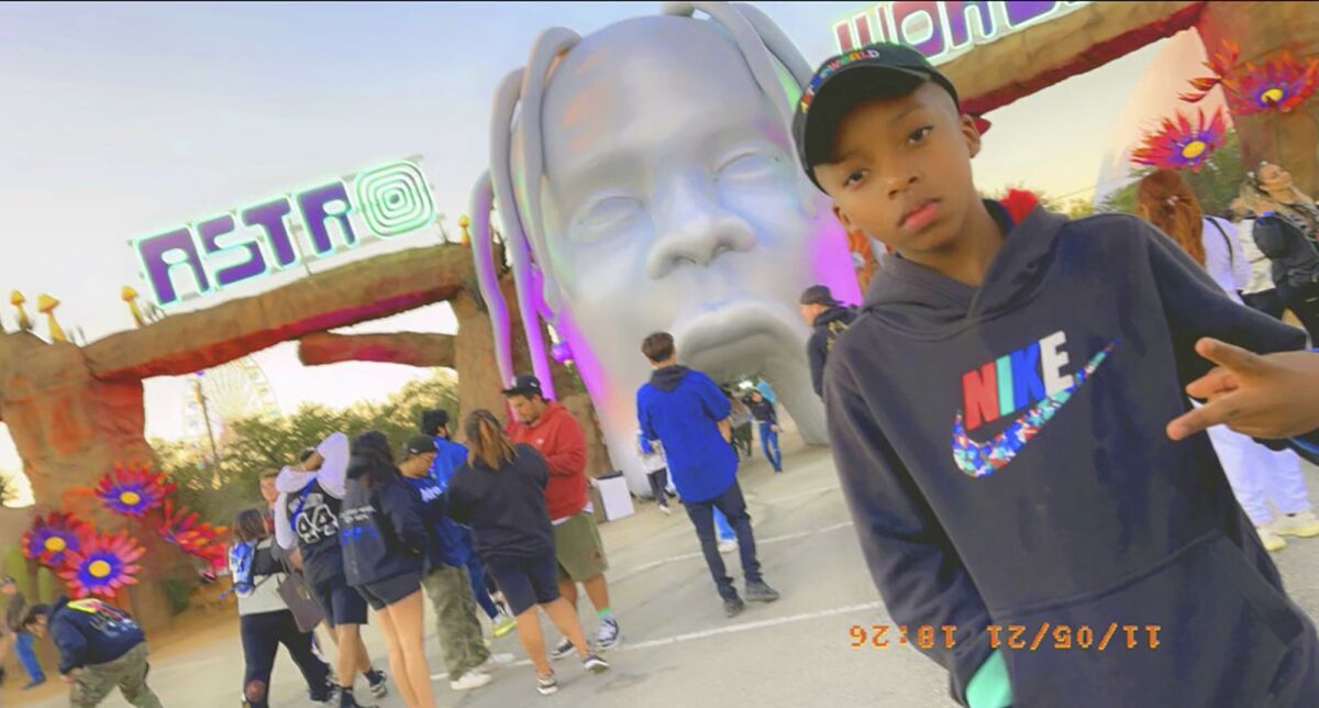 A boy poses for a photo in front of the gates to the Astroworld music festival