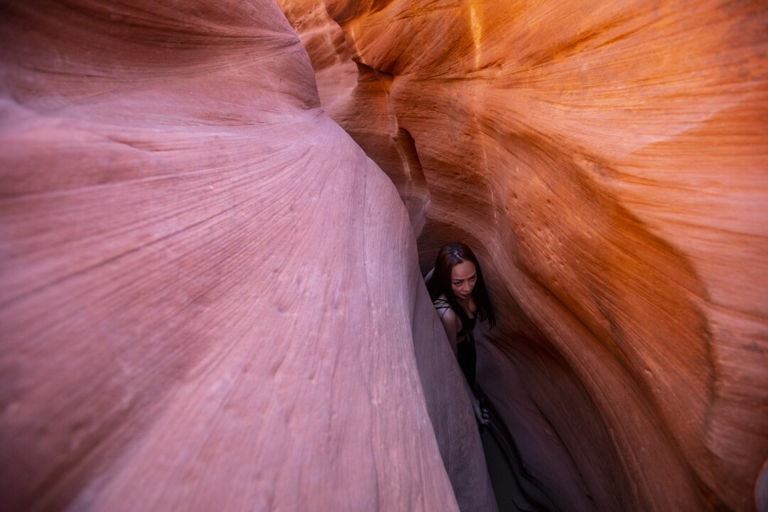 A hiker in the peach-colored labyrinth of Peek-a-Boo Canyon.