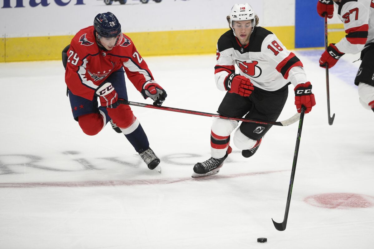 New Jersey Devils forward Dawson Mercer (18) skates with the puck ahead of Washington Capitals center Hendrix Lapierre (29) during the second period of an NHL preseason hockey game, Wednesday, Sept. 29, 2021, in Washington. (AP Photo/Nick Wass)