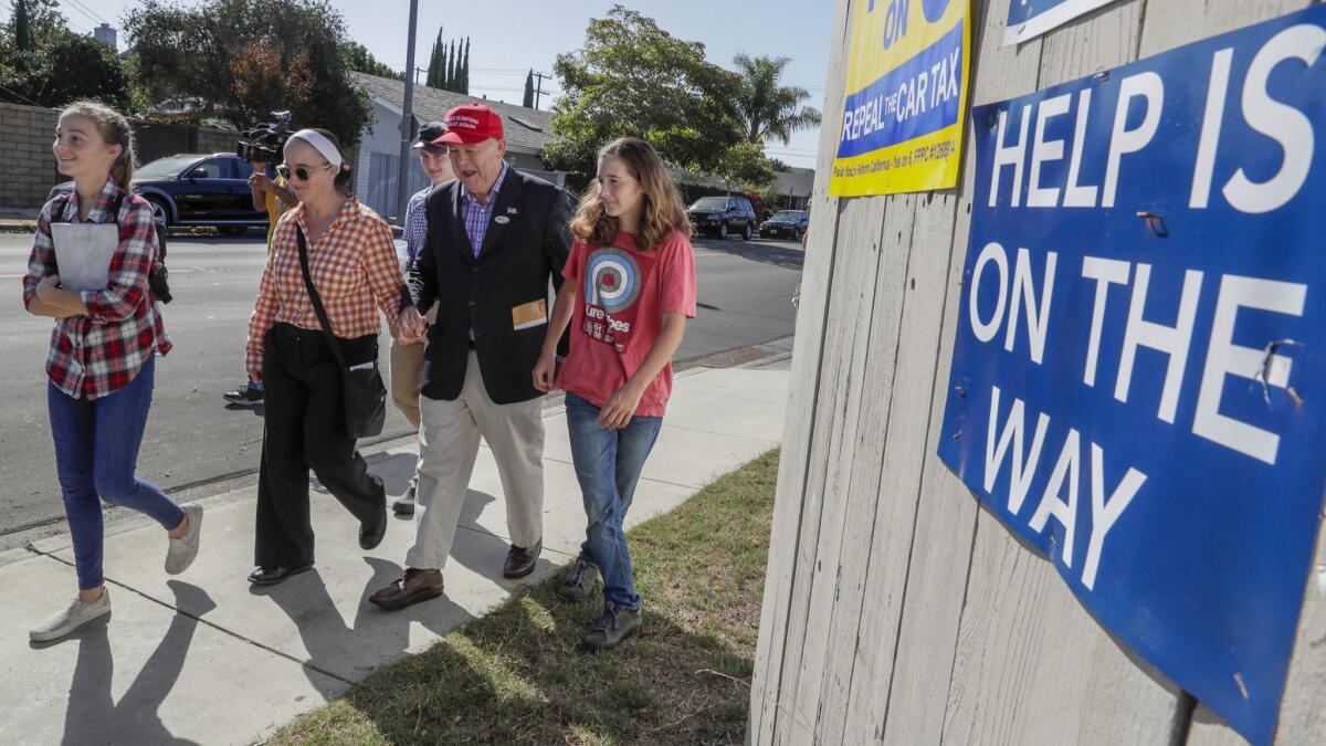 Republican Rep. Dana Rohrabacher walks with his wife, Rhonda, daughters Annika, left, and Tristen, and his son, Christian, back, as he drops off a mail-in ballot Tuesday at the Boys and Girls Club of Costa Mesa.