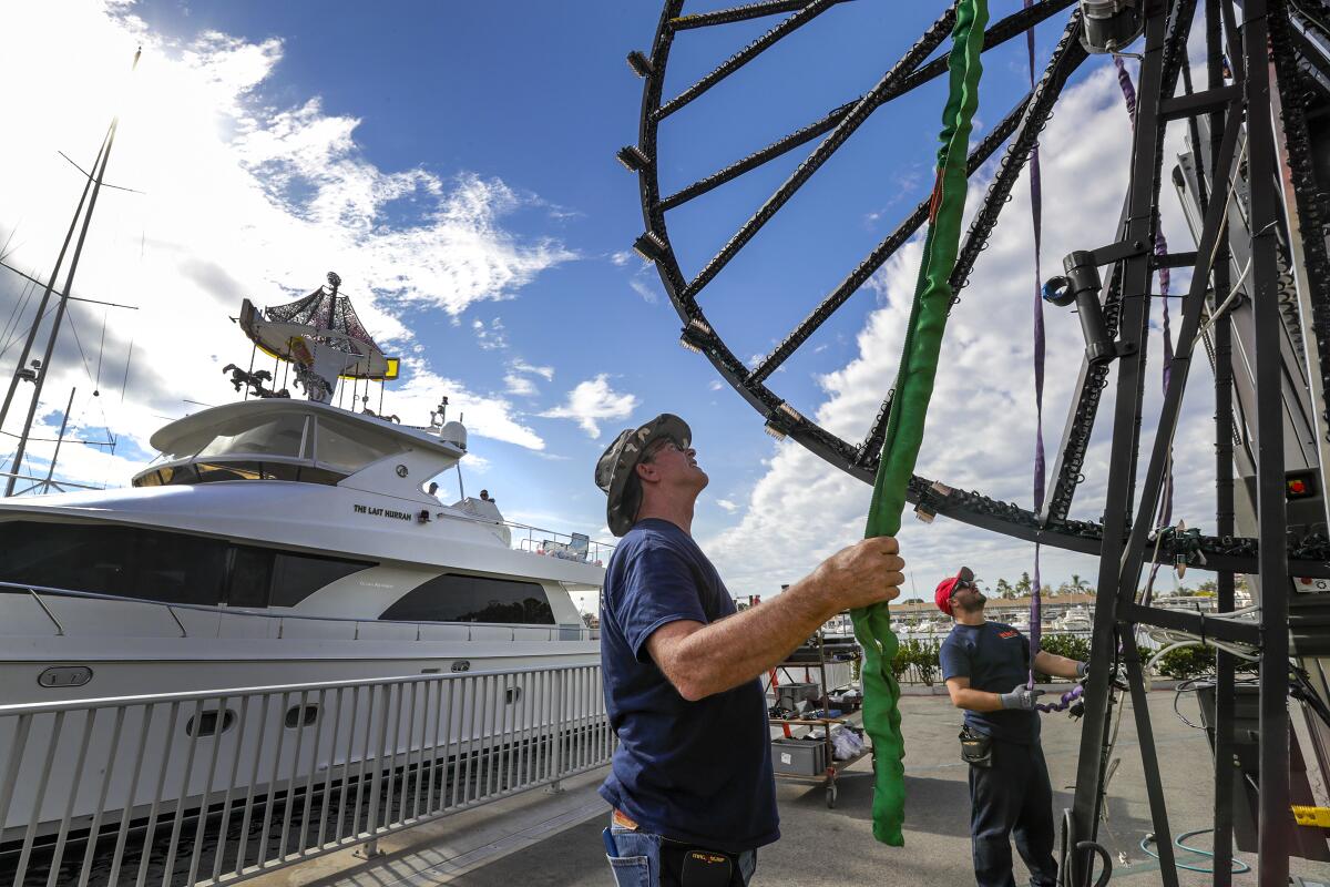 Jerry Clowes, foreground, installs a Ferris wheel on the yacht Last Hurrah for this year's Newport Beach Christmas Boat Parade.