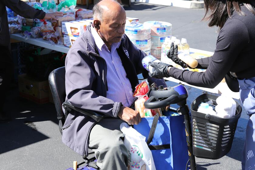 Anton Dabhi, 88, picks food from the Second Harvest Food Bank "Granny's Market" a park-it-market at Villa Anaheim Senior Apartments in Anaheim on Tuesday, April 2, 2024. The massive mobile walk-up market is housed in refrigerator for seniors to select fresh dairy, eggs, protein and produce all free of charge. (Photo by James Carbone)