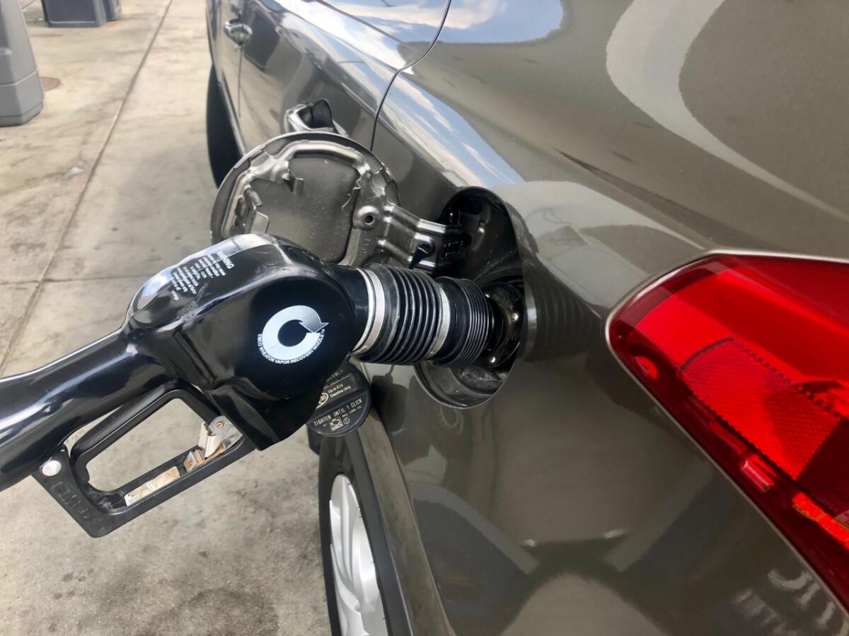 A gas pump nozzle stuck in a car gas tank's filler tube.