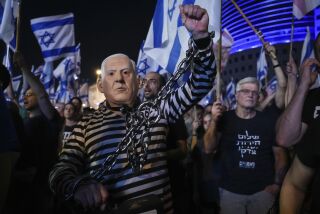 Numerosas personas, entre ellas una disfrazda del primer ministro israelí Benjamin Netanyahu encadenado, protestan contra los planes del gobierno de modificar el sistema judicial, durante una movilización en Tel Aviv, Israel, el sábado 10 de junio de 2023. (AP Foto/Tsafrir Abayov)