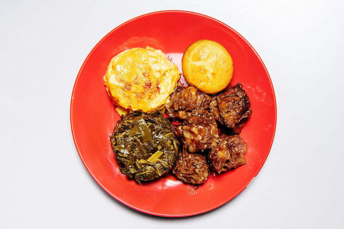 A plate with oxtail, collard greens, mac and cheese and cornbread 