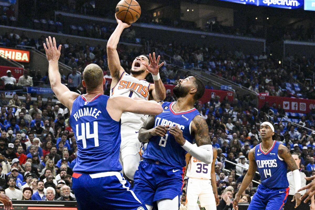 Phoenix Suns guard Devin Booker goes up for a shot in front of Clippers forward Marcus Morris Sr. and center Mason Plumlee.