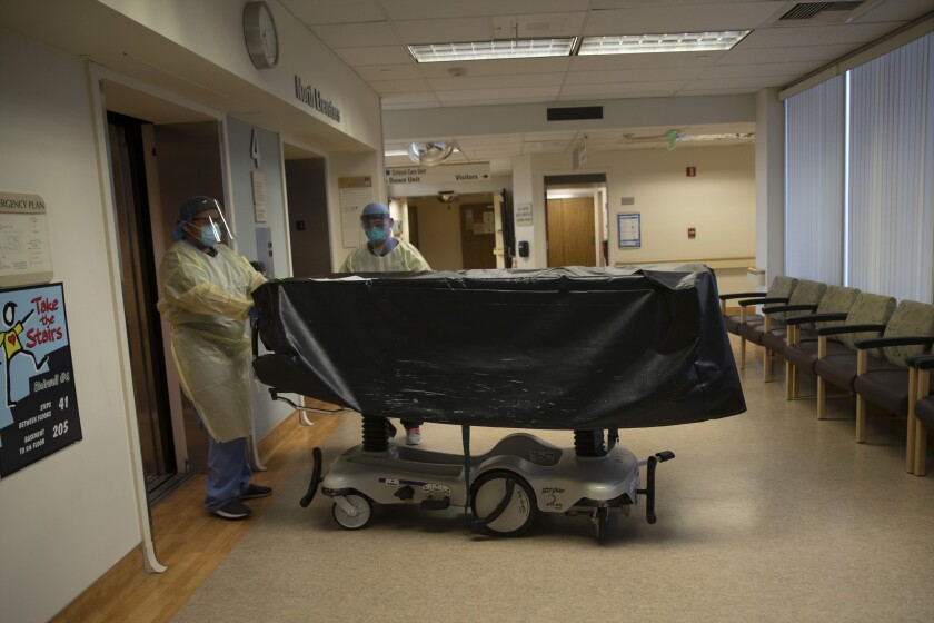 FILE - In this July 7, 2020, file photo, hospital staff members enter an elevator with the body of a COVID-19 victim on a gurney at St. Jude Medical Center in Fullerton, Calif. California health authorities reported on Saturday, Jan. 9, 2021, a record high of 695 coronavirus deaths as many hospitals strain under unprecedented caseloads. The state Department of Public Health says the number raises the state's death toll since the start of the pandemic to 29,233. (AP Photo/Jae C. Hong, File)