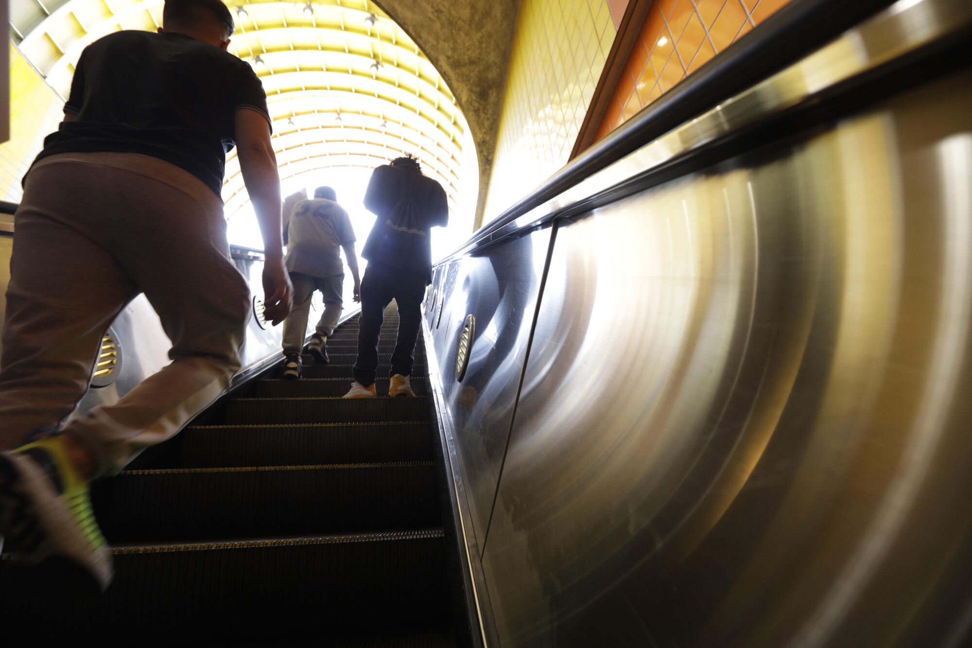 Commuters walking up an escalator